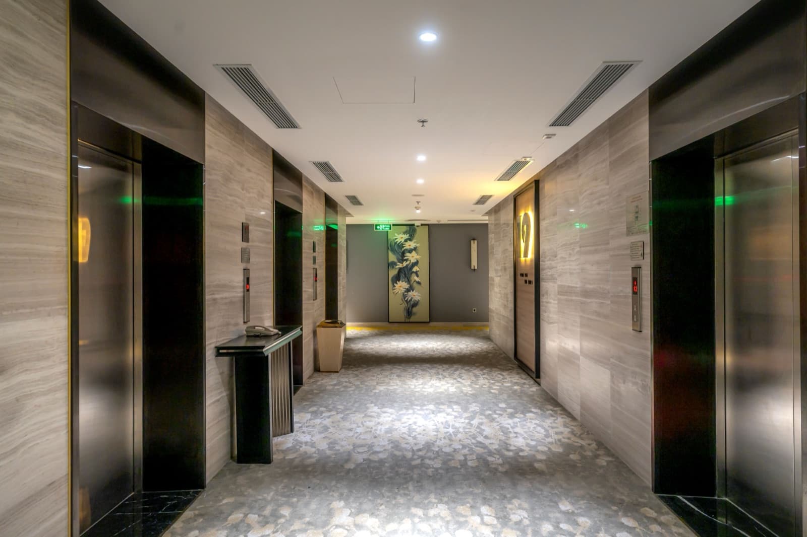 Stainless steel lift doors lining a marble hotel corridor