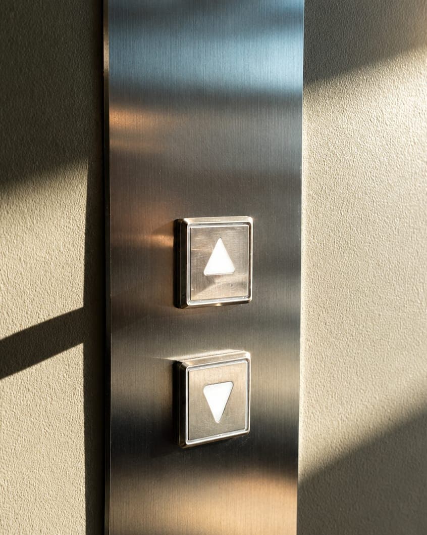 Sunlit lift call buttons on a brushed steel panel