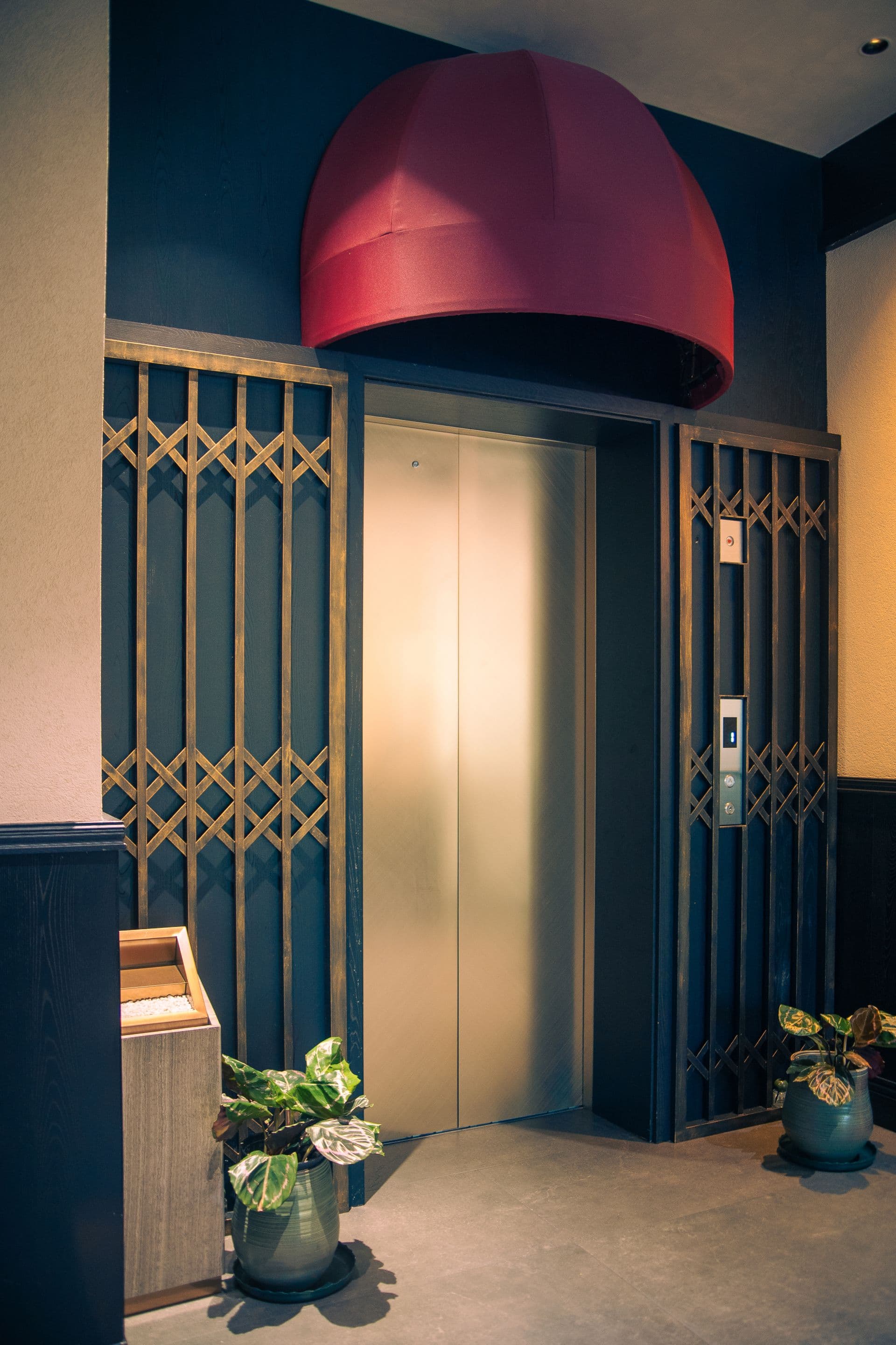 Brass lift doors framed by latticework in a hotel lobby